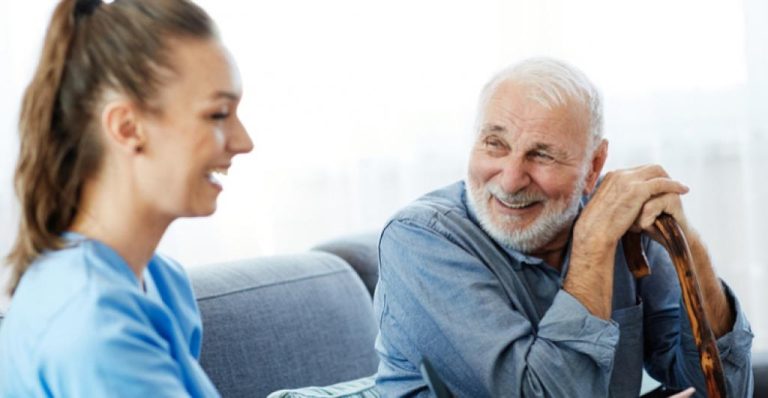 Eine junge Pflegefachkraft der IAHA im Gespräch mit einem älteren Mann – ein Beispiel für die wertvolle Unterstützung, die pflegende Angehörige im Alltag entlastet.